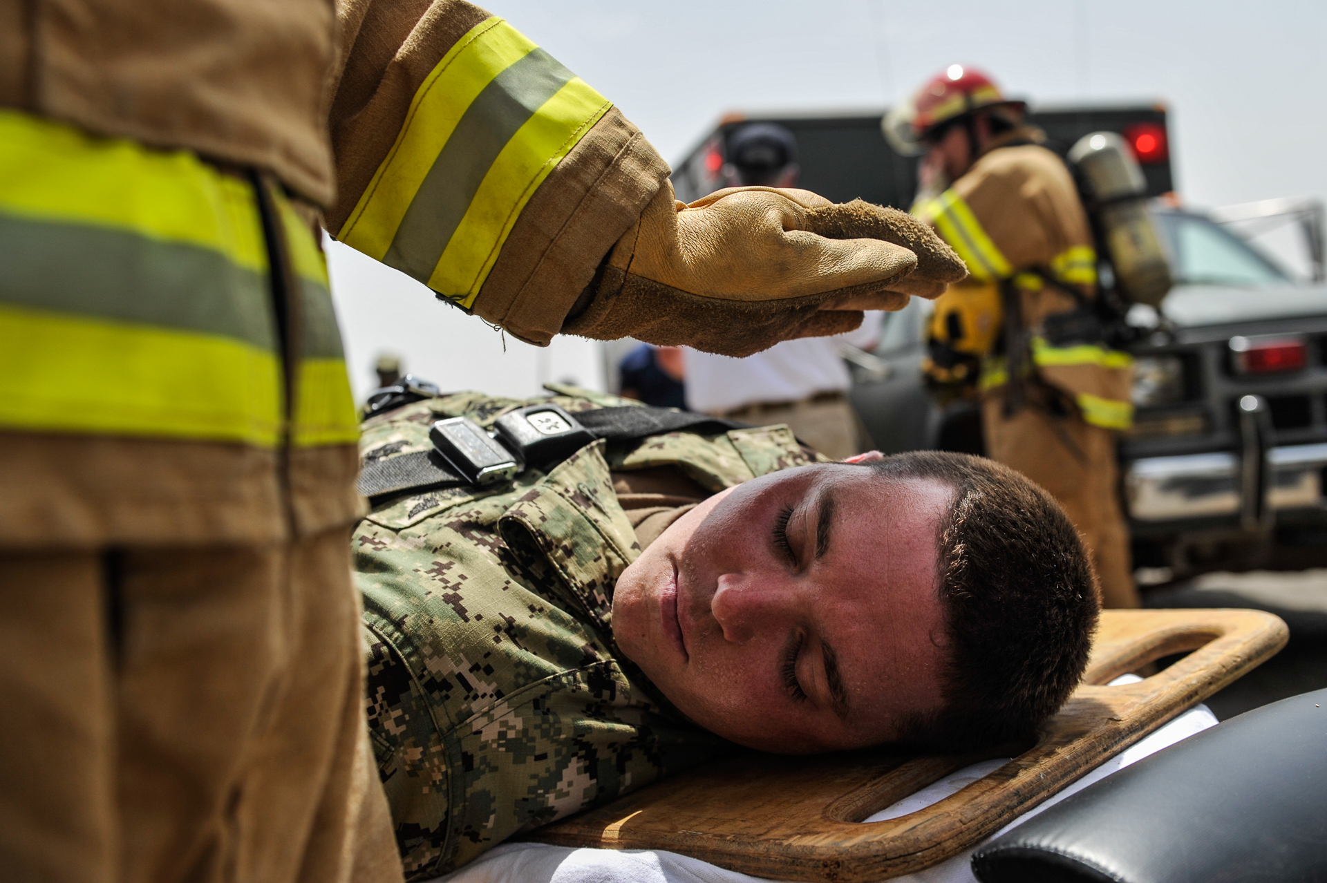 A firefighter shades the face of U.S. Navy Air Traffic Controller 2nd Class Eric Jennings during a mass casualty exercise on Camp Lemonnier, Djibouti, July 25, 2013. The exercise tested the ability of camp emergency and medical personnel to respond to a simulated chemical nerve agent attack. (Eric Dietrich/U.S. Navy)