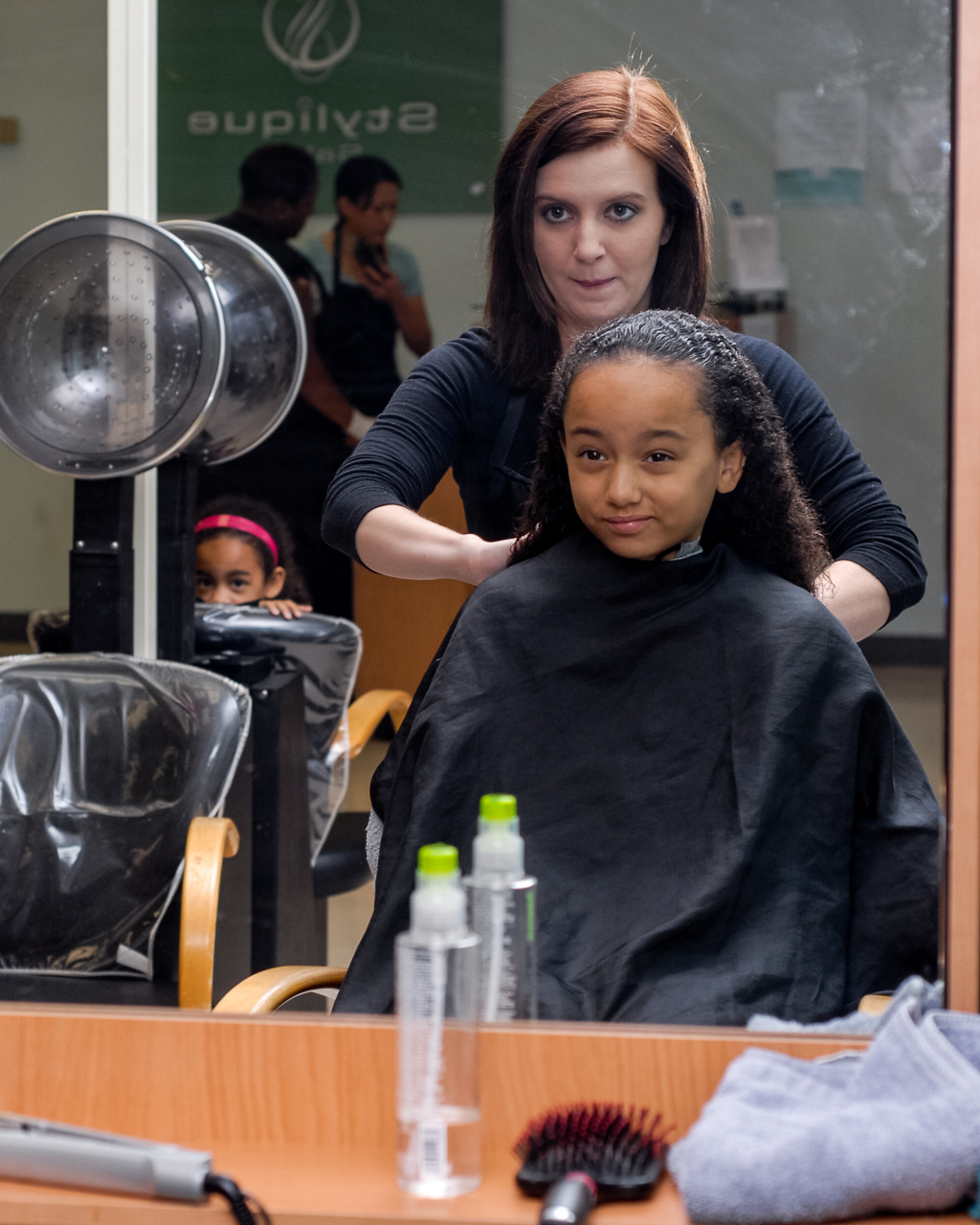 Samantha Goins, a cosmetologist at Stylique Salon on Fort George G. Meade, Md., cuts customer Ania Williams' hair while her sister watches, Oct. 1, 2011. (Eric Dietrich/U.S. Navy)