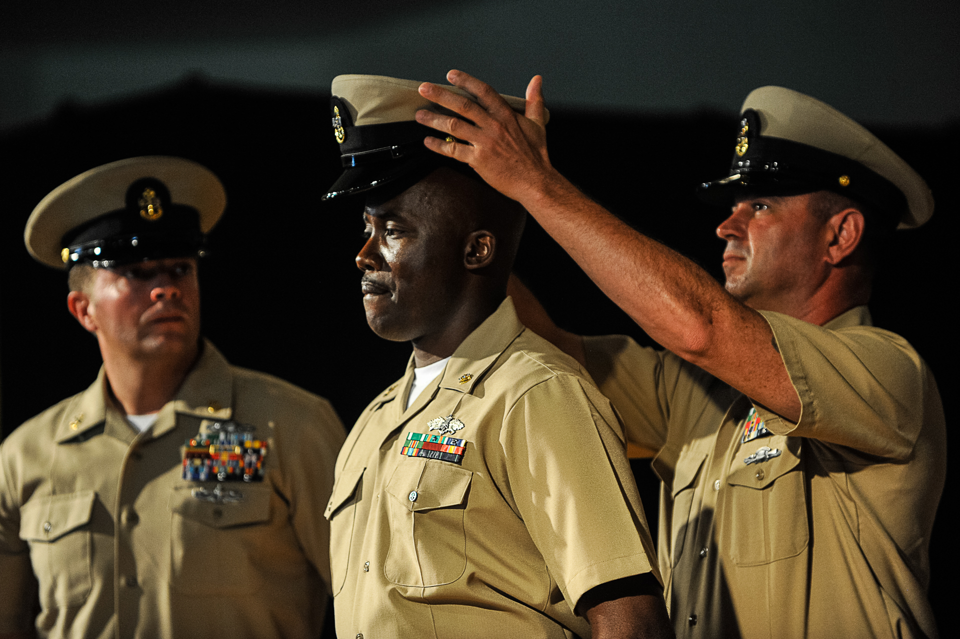 Senior Chief Petty Officer James Strong places a cover on Chief Equipment Operator Roderick Nelson during a chief petty officer pinning ceremony held at Camp Lemonnier, Djibouti, Sept. 13, 2013. Eighteen first class petty officers were advanced to chief petty officer during the ceremony. (Eric Dietrich/U.S. Navy)